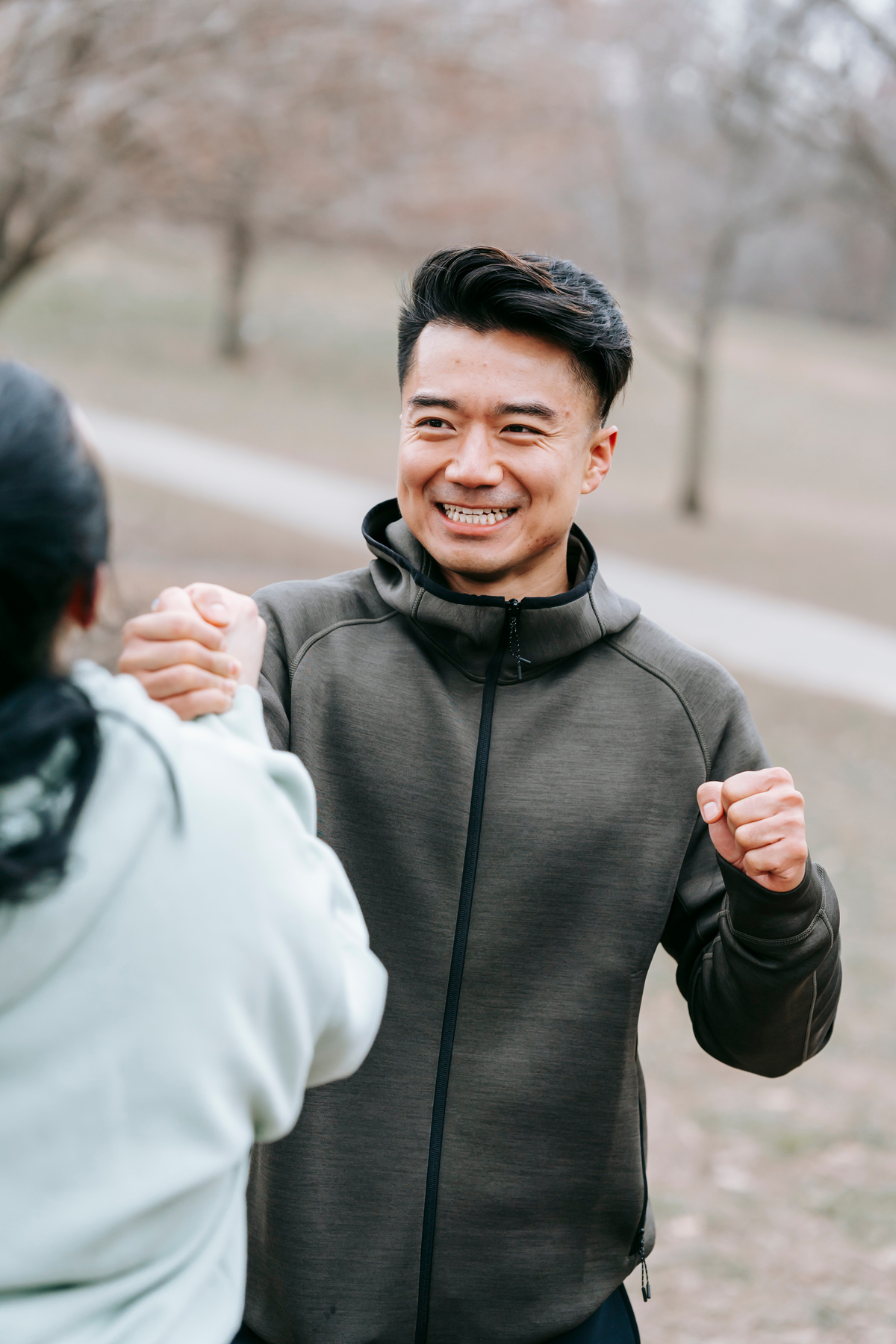 Happy Asian man holding hand of woman in park